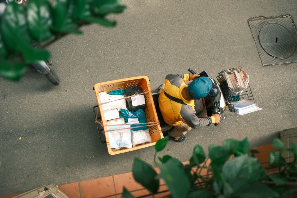 Courier on a scooter viewed from above delivering packages on a sunny day.