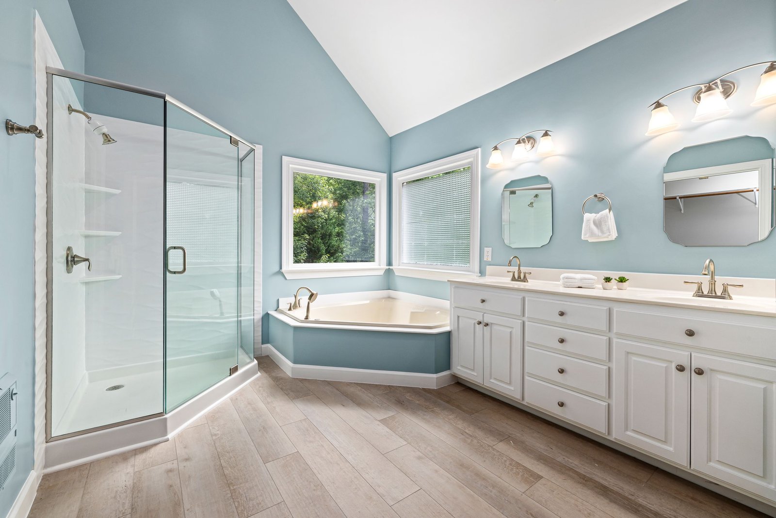 Elegant bathroom interior featuring a glass shower, bathtub, and dual sink vanity.